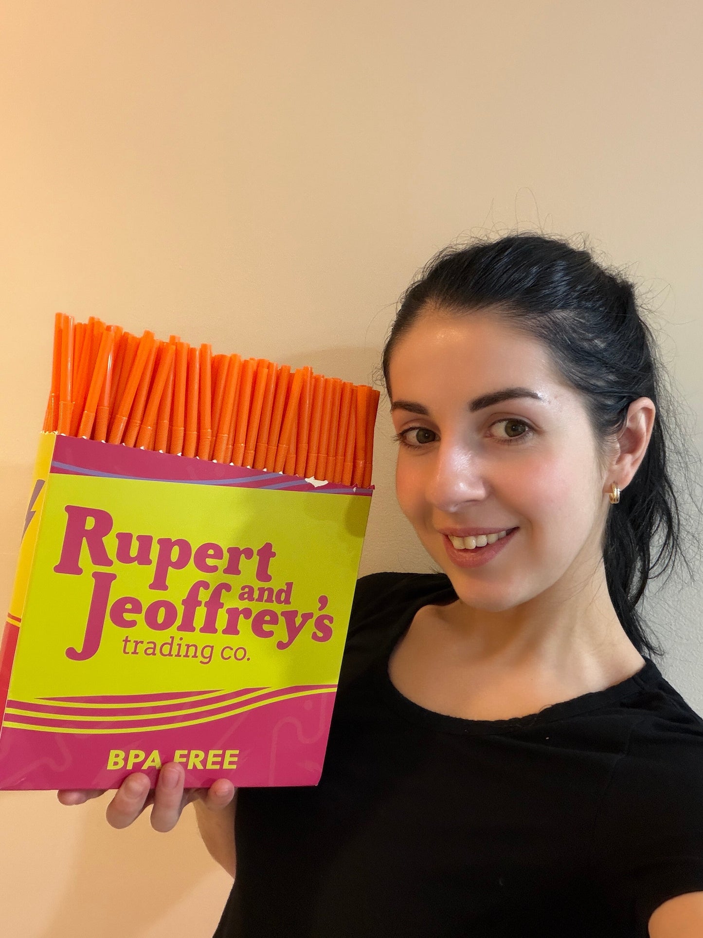 Woman holding a box of orange extra flexible art straws by Rupert and Jeoffrey's trading co. BPA free